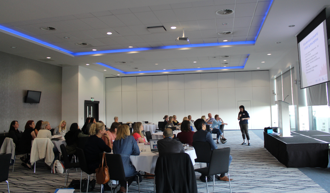 An event with a room full of guests listening to a speaker present