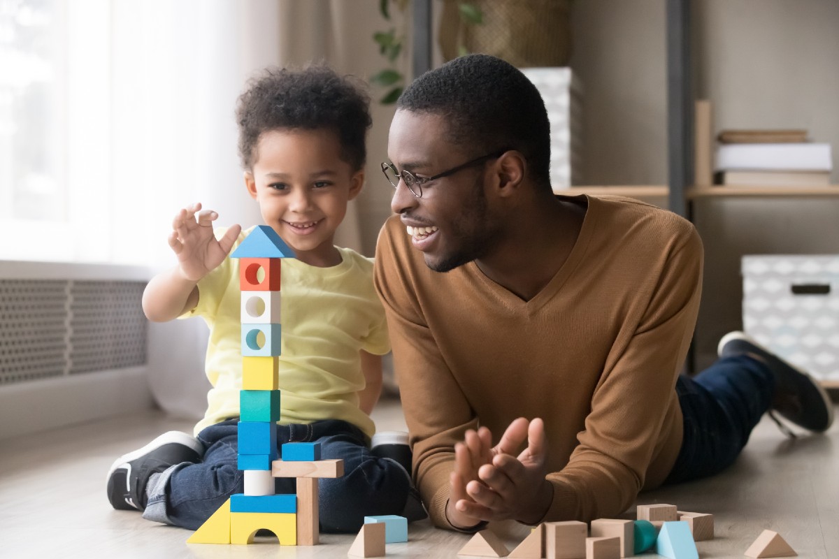 Young child and father learning and playing with blocks on the floor