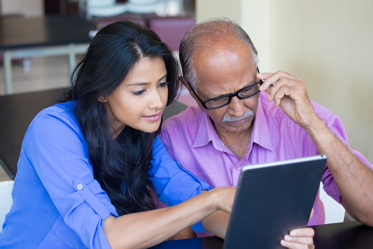 Young woman and elderly man using tablet computer