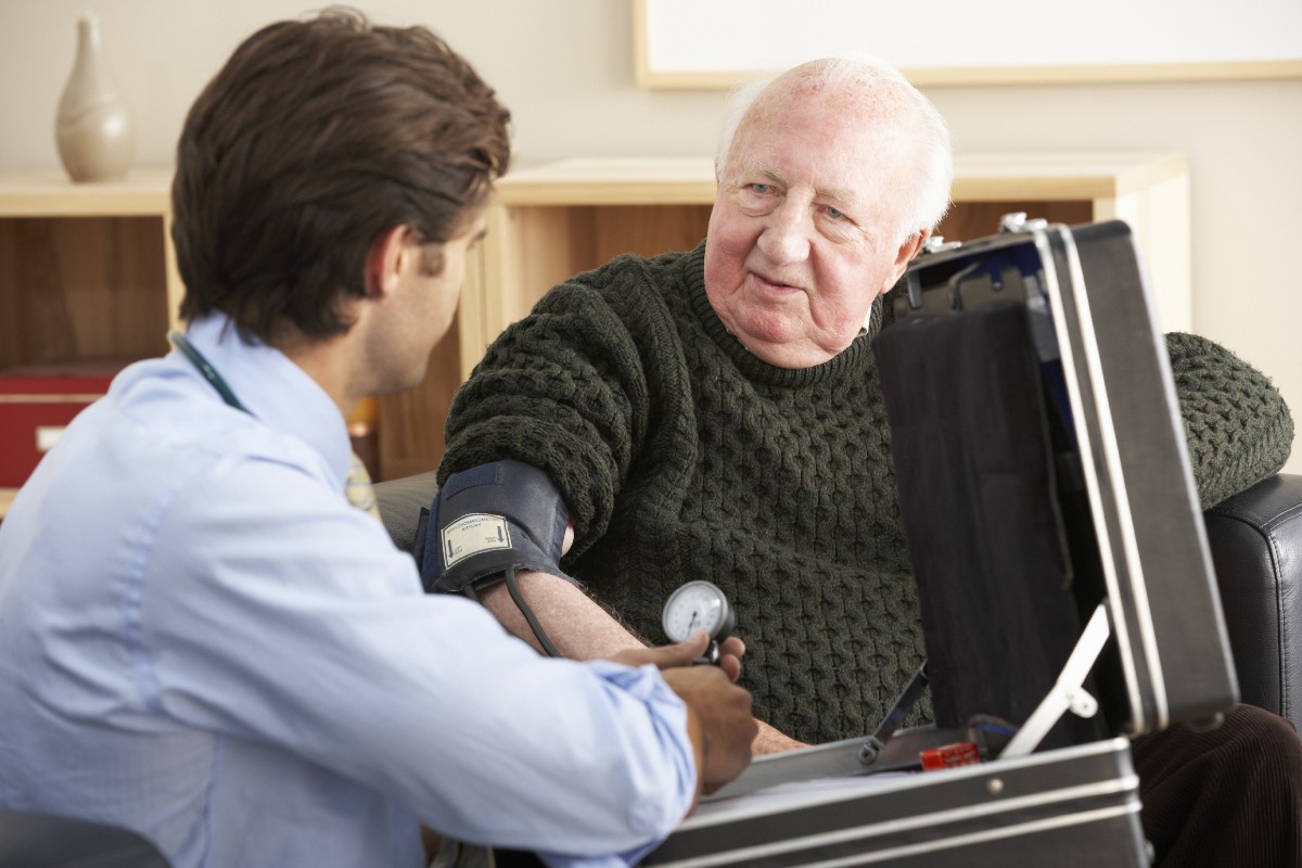 Elderly man has blood pressure checked by doctor