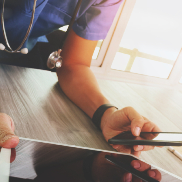 A nurse holding a phone and an ipad/tablet.