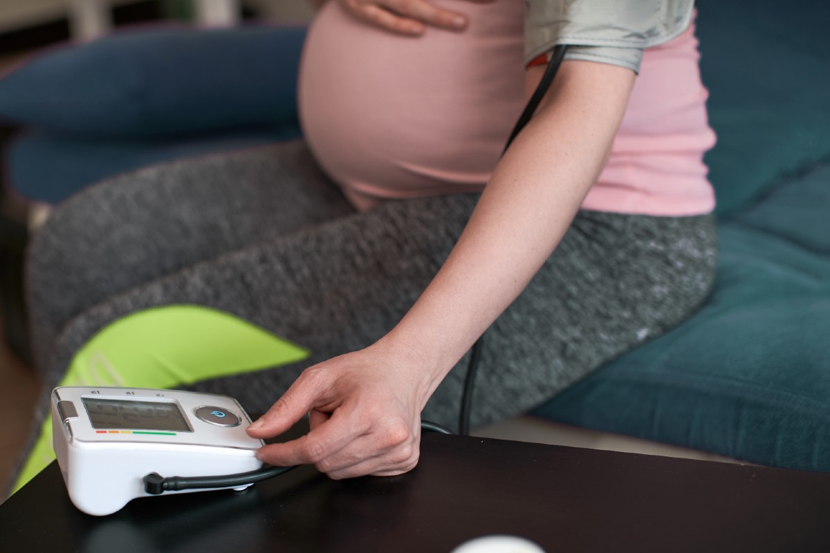 Pregnant woman at home uses a blood pressure monitor