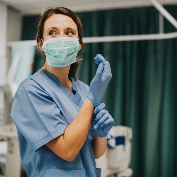 Healthcare worker in a hospital setting putting on PPE