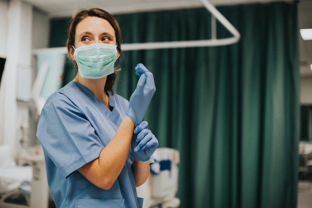 Healthcare worker in a hospital setting putting on PPE