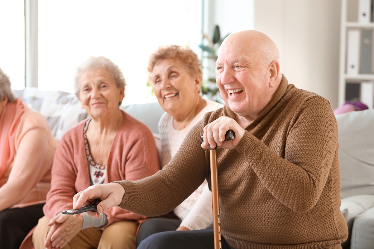 Two older women and an older man enjoying watching digital television together