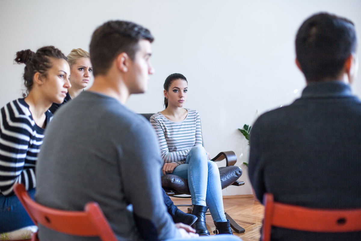 A community group of people, both men & women, sat having a discussion